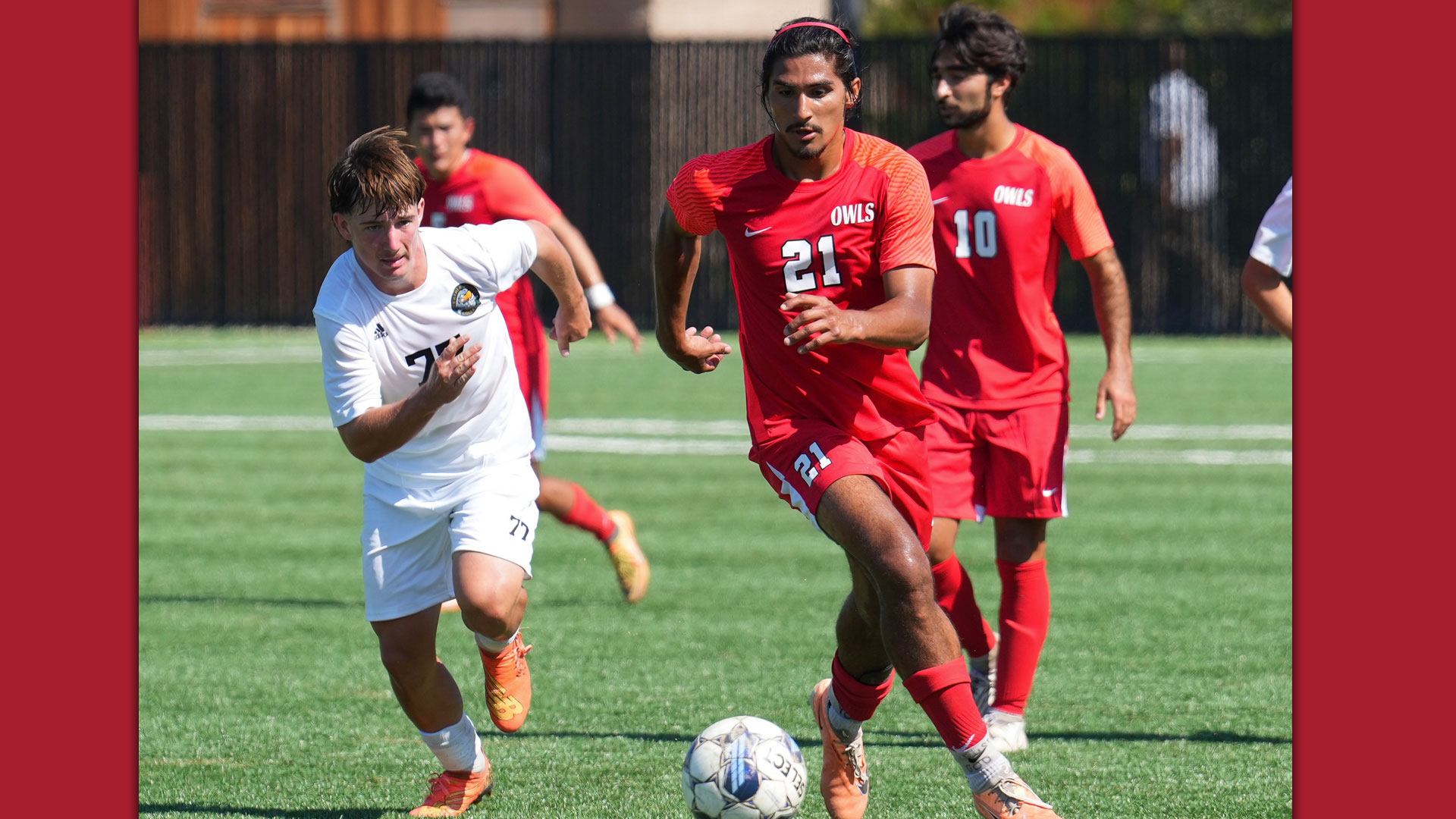 player in red jersey and white #21 dribbling ball away from defender in white jersey